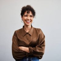Portrait of a young businesswoman smiling while standing with her arms crossed in front of a white wall in an office